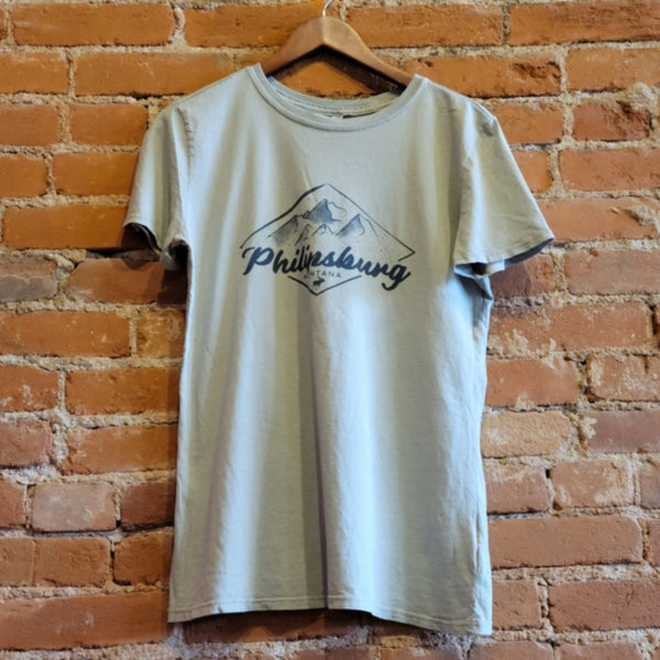Front of Ouray women's mineral wash, crew neck T-shirt in the colorway Desert Sage (light olive green). "Philipsburg Montana" is printed in a dark green text with a small moose silhouette below the text. Snowy mountains are above the text in the same dark green ink.