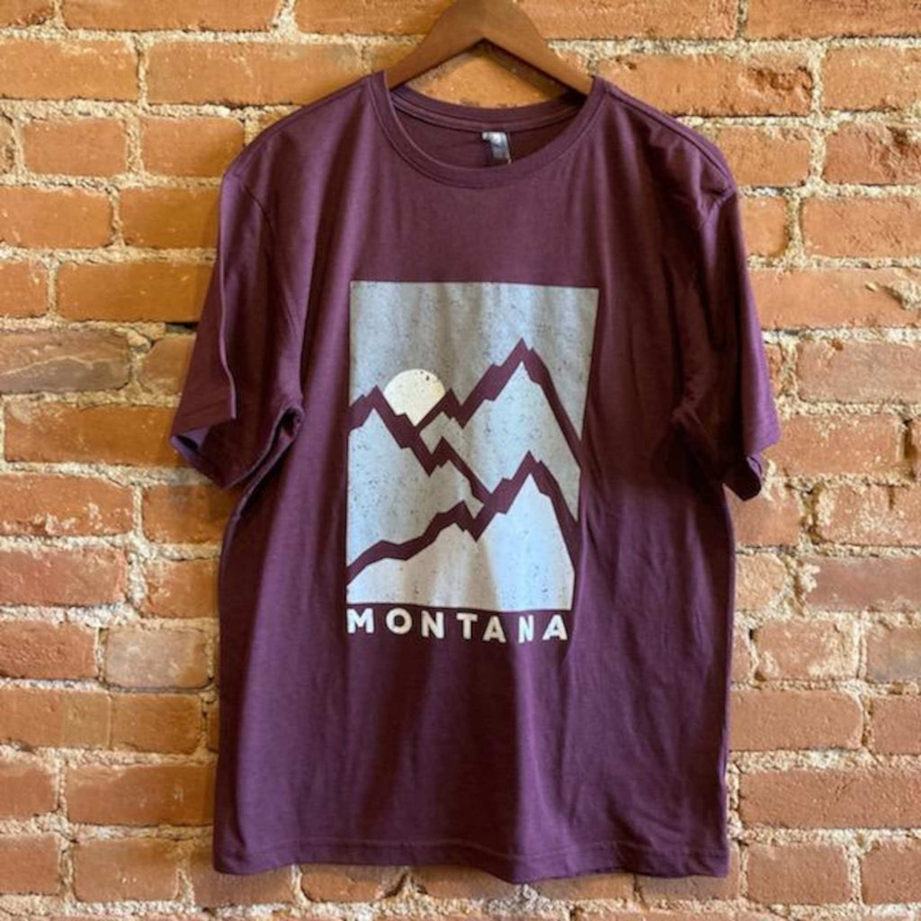 Front veiw of the Men's Crew Neck T-Shirt with Mountain Print. The Fabric is dark red with a grey rectangle in the center of the shirt. Three mountain slopes are outlined in the same dark red color with a white sun in the sky. "Montana" is printed below the image in light grey.
