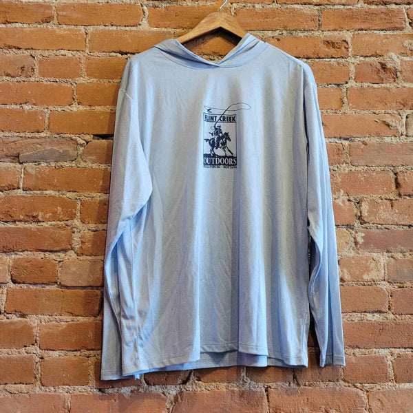 Picture of the women's sun hoody front in the colorway Blue Fog (light blue). There is a white print of the Flint Creek Outdoors Logo of a cowboy on a horse fly-fishing on the front. 